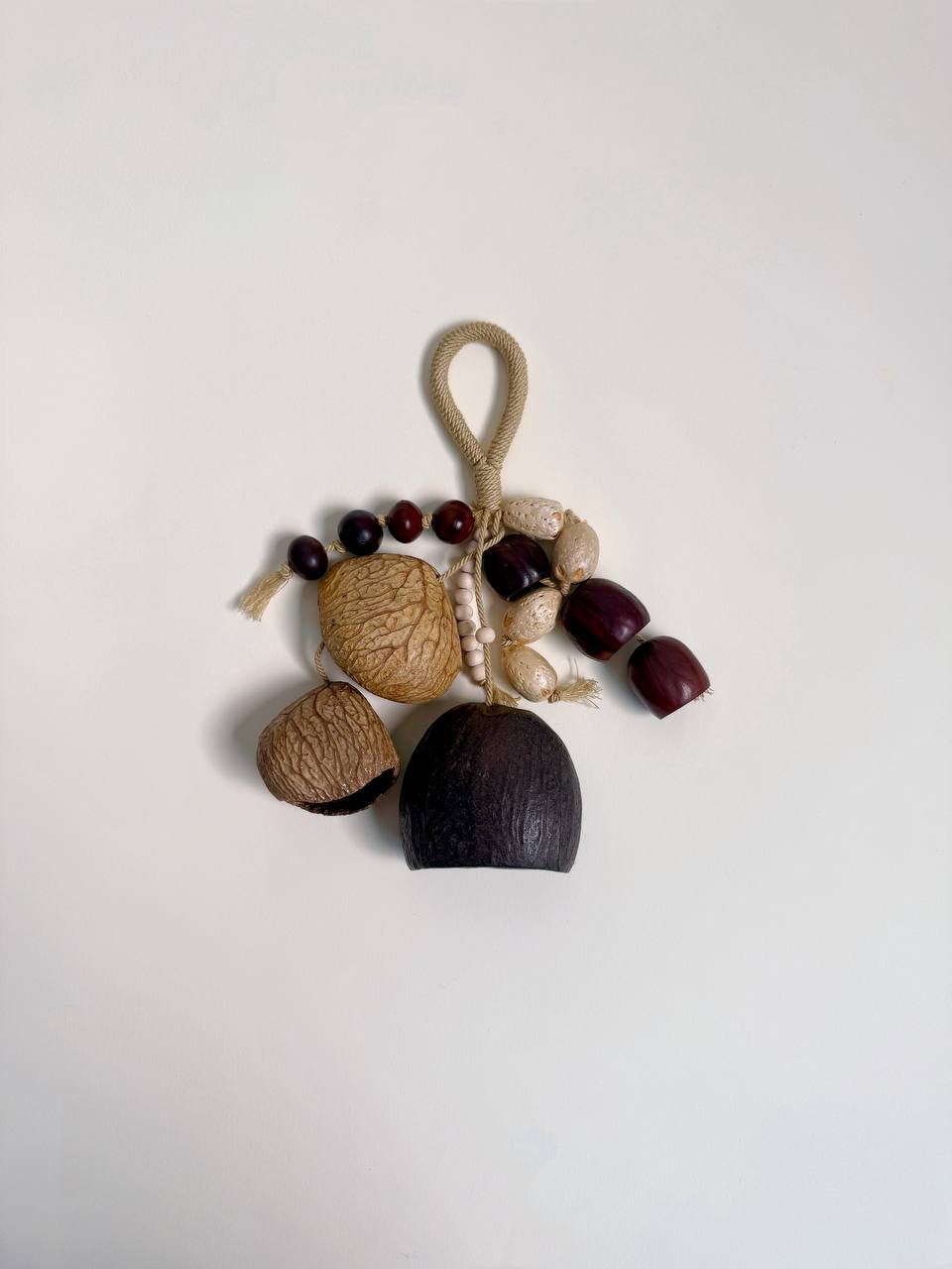 Decorative hanging with acorns, nuts, and beads on a white background